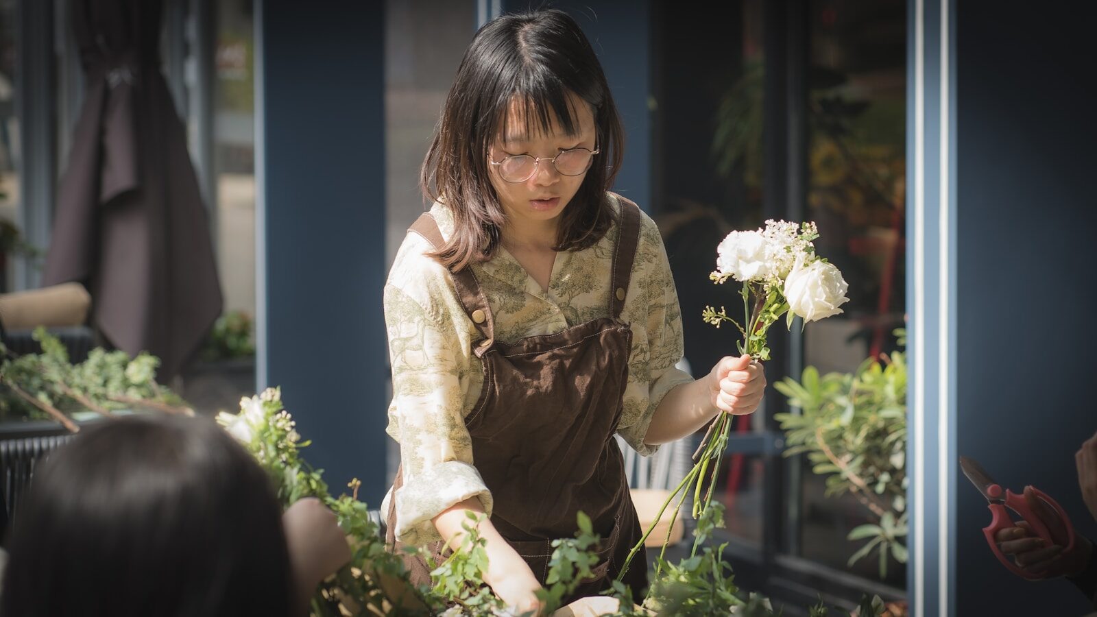 woman in brown long sleeve shirt holding white flower